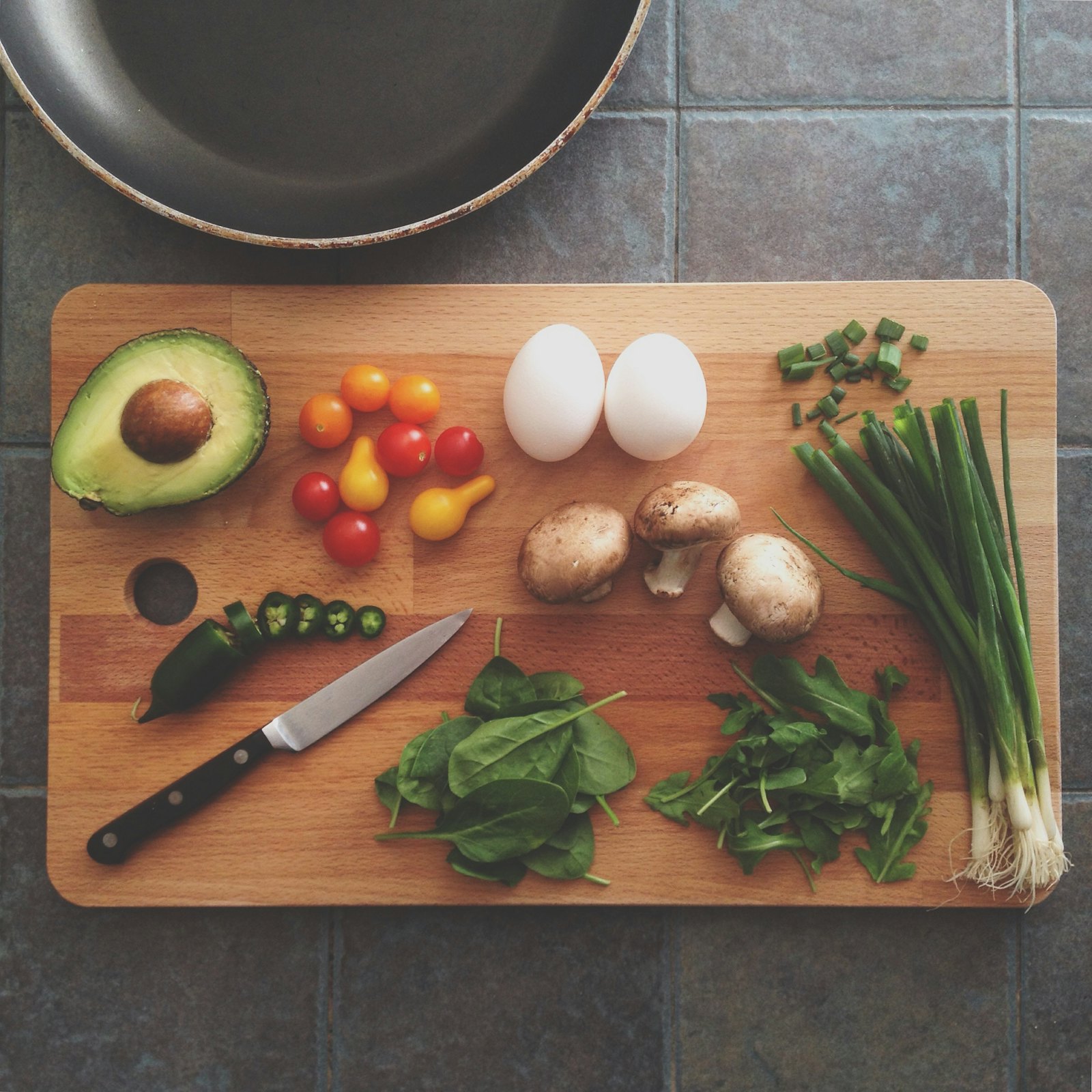 Avocado, eggs, tomatoes and herbs on a chopping board